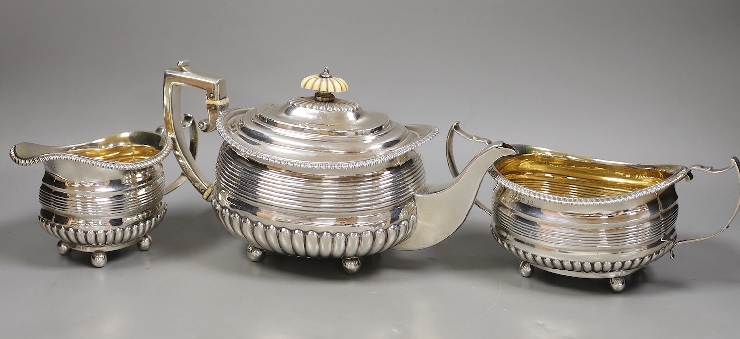 A matched George III demi fluted and reeded silver three piece tea set by Alice & George Burroughs and Walter Bennett (teapot patched), London, 1813, with ivory knop and insulators